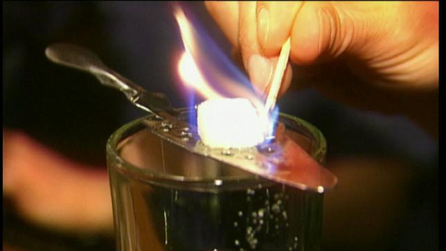 Ein Absinth wird mit einem brennenden Stückchen Zucker gesüßt.