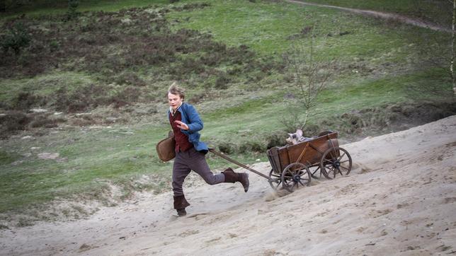 Hans (Anton Spieker) ist mit seinem getauschten Schwein im Bollerwagen im Glück.