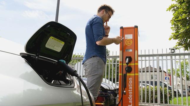 Bild: WDR Elektroauto beim Tanken an Ladestation, Mann schaut fragend auf sein Handy