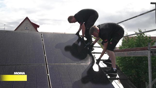 Heinzungsbauer Florian Schöpfer und sein Kollege installieren Solarpanele auf einem Dach