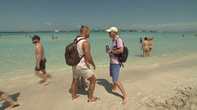 MOMA-Reporter Sebastian Kisters spricht mit Touristen am Strand von Ibiza.