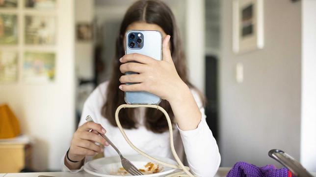 Jugendliche hält sich ein Handy vor das Gesicht