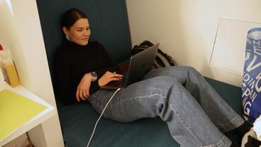 Eine Frau sitzt mit ihren Laptops auf dem Boden.