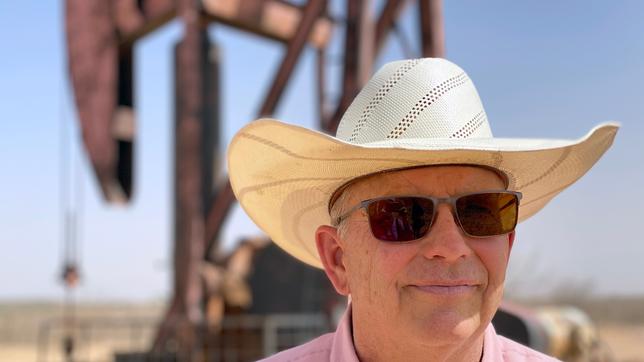 Mann mit Cowboyhut, im Hintergrund eine Ölförder-Anlage.