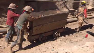 Minenarbeiter ziehen Güterlore ins Bergwerk