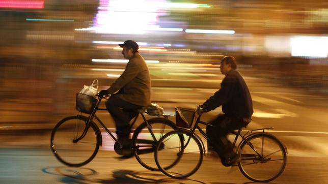 Zwei Menschen unterwegs auf Fahrrädern in der Nacht. 