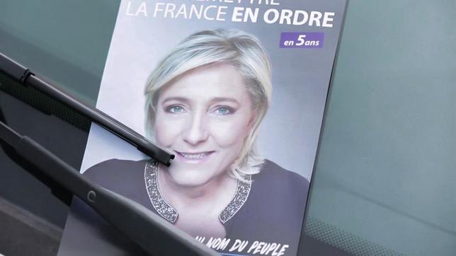 Ein Flugblatt mit Marine Le Pen hängt an einem Autofenster.