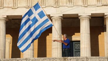 Bild: picture alliance / ZUMAPRESS.com Ein Mann mit der griechischen Flagge vor dem Parlament in Athen
