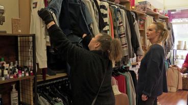 Frau schaut Kleidung in Second-Hand-Laden an 