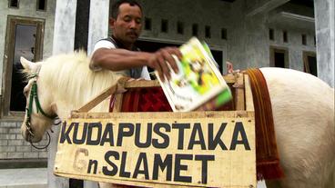 Ein Mann nimmt Bücher aus einer Holzbox, die als Satteltasche dient