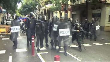 Spanische Polizei mit Schlagstöcken. Ein Polizist schießt mit Gummigeschossen.