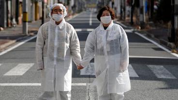 Ehepaar in Strahlenschutzkleidung in Namie bei Fukushima.