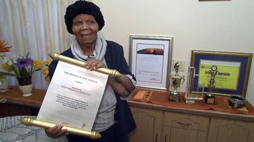Nontsikelelo Qwelane hält eine Urkunde in der Hand.