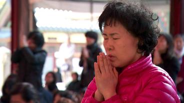 Ein Mutter betet für ein gutes Abitur des Kindes.