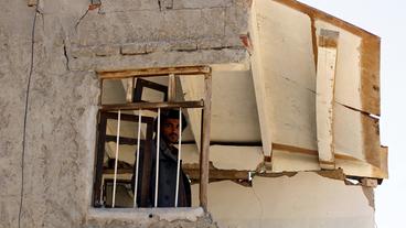 Ein Mann blickt in Sanaa aus einem zerstörten Haus