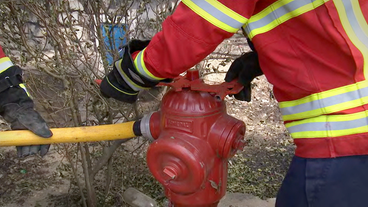 Feuerwehrmänner schließen Schlauch an Hydrant an