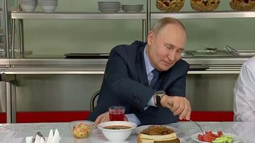 Präsident Putin zu Besuch in Agrarbetrieb beim Essen einer Tomate