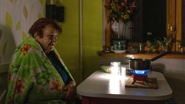 Eine ältere Frau kocht während eines Stromausfalls Essen auf einem Gasbrenner.