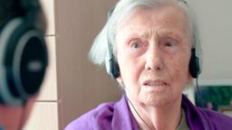 Eine ältere Dame hört Musik.