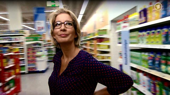 Yvonne Willicks steht in der Sendung "Der Haushalts-Check mit Yvonne Willicks" zwischen Supermarktregalen mit Putzmittel.