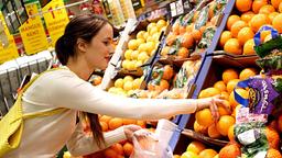 Frau kauft Orangen im Supermarkt