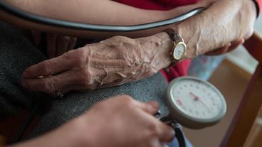 Eine Bewohnerin einer Seniorenwohnanlage bekommt den Blutdruck gemessen. 