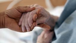 Die Hand einer alten Person wird gehalten.