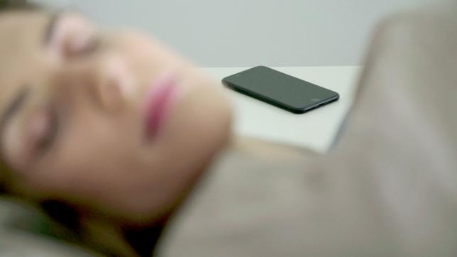 Schlafende Frau, im Hintergrund liegt ein Handy