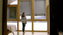 Mdchen steht vor Fenster, whrend Rolladen runterfhrt.