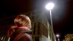 Eine Frau steht unter einer Straenlaterne.
