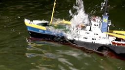 Modellschiff wird von einer Welle berrollt.