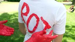 Student schreibt mit roter Fingerfarbe das Wort ?rot? auf weies T-Shirt