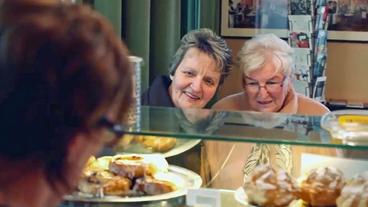 Zwei ältere Damen vor Kuchentheke im Café