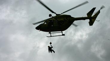Ein Rettungshelfer hängt an einem Helikopter