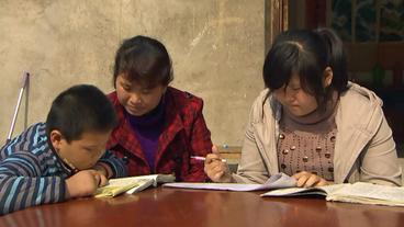 Eine Frau hilft zwei Kindern beim Lernen