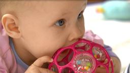 Ein Baby kaut an einem Ball.