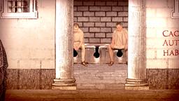 Gruppe von Mnnern in Togen sitzen nebeneinander auf einer Latrine.