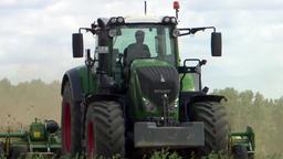 Traktor mit angehngter Egge beackert ein Feld 