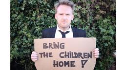 Axel Stein mit einem Schild mit der Aufschrift "Bring the children home"