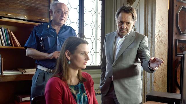 Bildquelle: ARD Degeto/ Nicolas Maas Commissario Brunetti (Uwe Kockisch, re.), Sergante Vianello (Karl Fischer) und Signora Elettra (Annett Renneberg) ermitteln in dem mysteriösen Mord an dem ehemaligen Theologen Enrico Franchini. Dabei begeben sie sich in eine Zeitreise ins Venedig des 16. Jahrhunderts. Die Spur führt in die traditionsreiche Bibliothek Merula, in der in letzter Zeit Seiten aus wertvollen historischen Büchern entwendet wurden.