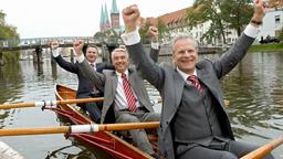 Drei Mann in einem Boot: Bürgermeister Schneider (Peter Sattmann, vorne), Bauamtsleiter Otto Schlegel (Christoph M. Ohrt, Mitte) und Pressesprecher Droller (Oliver Breite).