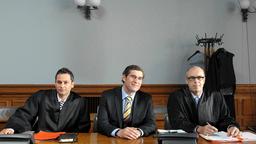 Flankiert von seinen Anwälten Braun (Peter Kremer, re.) und Rigas (Vassily Kazakos, li.) gibt der angeklagte  Bürgermeisterkandidat René Tornow (Stephan Szasz) sich siegesgewiss.