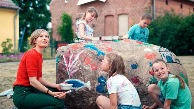 Bild: WDR/zischlermann/Simone Weigelt Anja (Alina Levshin) bemalt mit den Grundschulkindern den Gedenkstein als Zeichen gegen Rechts.