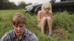 Tatort München: Benny (Max von der Groeben) sitzt geschockt und mit blutverschmiertem Gesicht im Gras, im Hintergrund Mia Petrescu (Mercedes Müller).