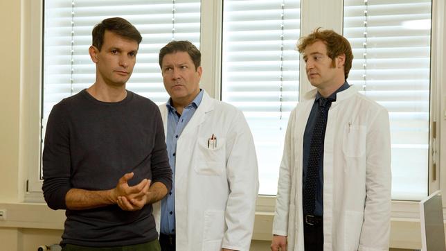 Bild: ARD/Volker Roloff Dr. Christian Kleist (Francis Fulton-Smith) und Dr. Timotheus von Hatzfeld (Tom Radisch) machen sich Sorgen um Dr. Michael Sandmann (Luca Zamperoni, l), der während einer Operation plötzlich Lähmungserscheinungen an der rechten Hand bekam. Eine Spätfolge des Kletterunfalls?