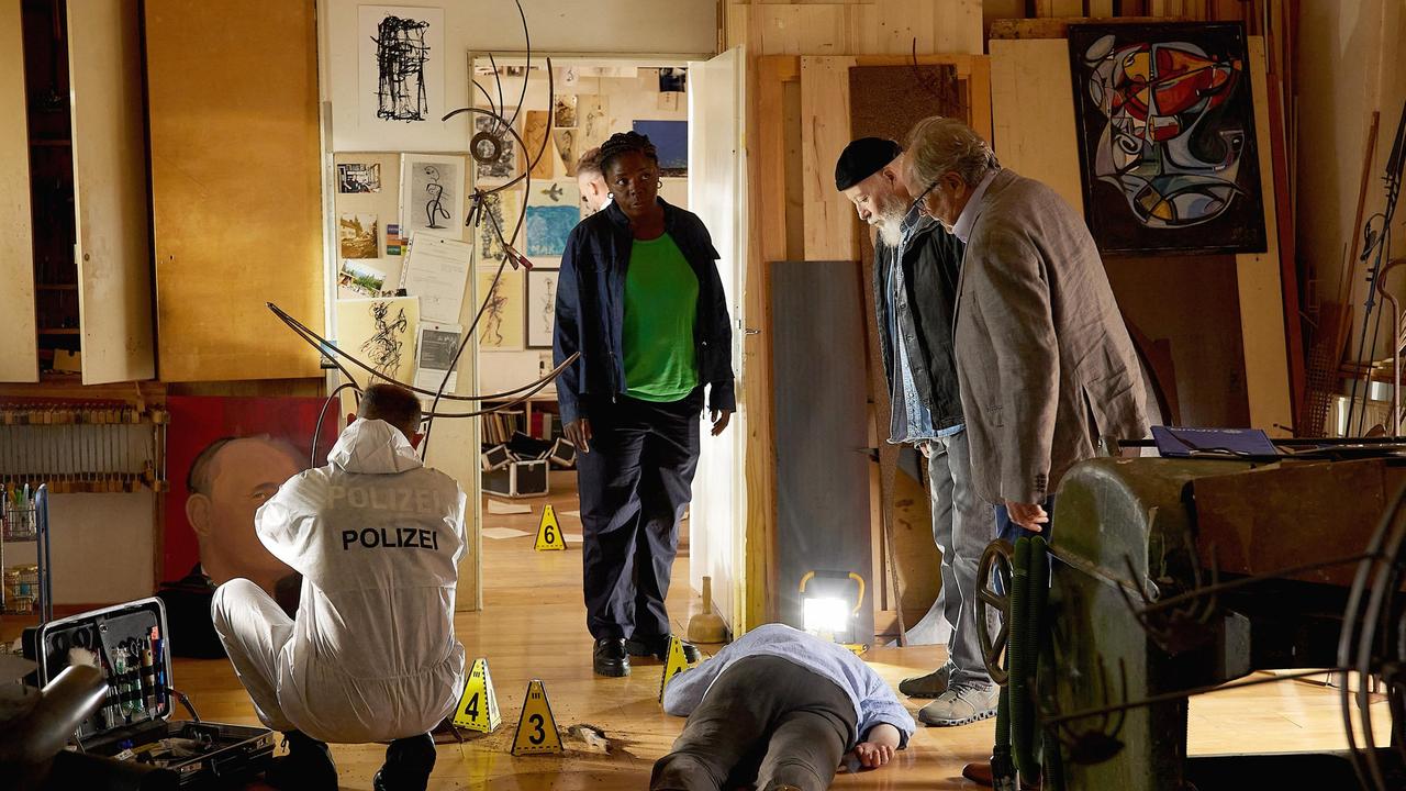 Künstler Domenicus Illner (Thomas Fehlen, liegend mit Komparse) liegt tot in seinem Atelier. Reinhard Bielefelder (Bill Mockridge), Klaus Schmitz (Hartmut Volle) und Dr. Lara Krüger (Dela Dabulamanzi) untersuchen den Tatort.