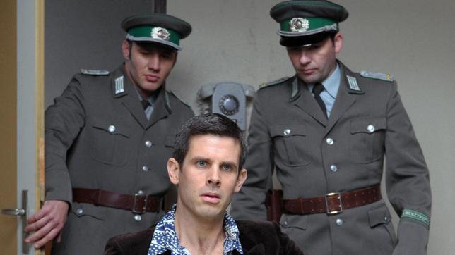 Robert Schnyder (Steffen Groth) wird wegen Beihilfe zur Republikflucht inhaftiert und im Vernehmungsraum von Falk verhört.