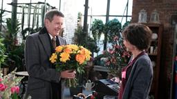 Gunter (Hermann Toelcke) freut sich auf die Ankunft seiner Schwester und kauft Blumen bei Merle (Anja Franke).