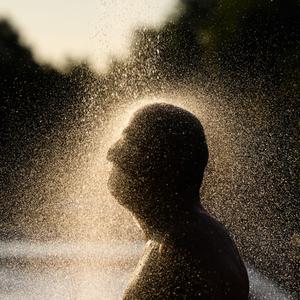 Ein Mann duscht am frühen Morgen im Freibad Annabad im Licht der aufgehenden Sonne.