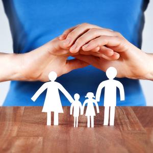 Hände werden über eine aus Papier ausgeschnittene Familiengruppe gehalten